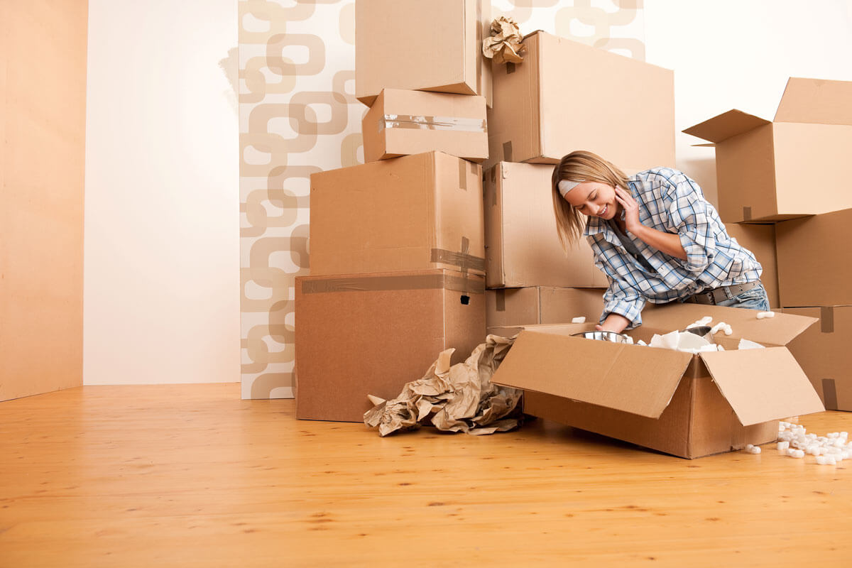 Get ready for a last-minute move, a young woman packs a moving box.